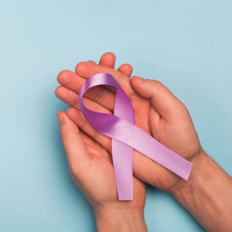Hands cradling a purple cancer awareness ribbon