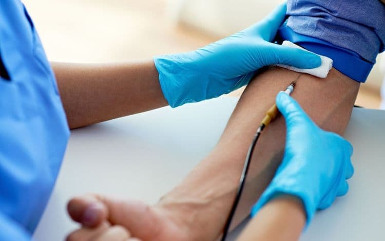 Bluecrest employee putting a needle into someone's arm to draw blood.
