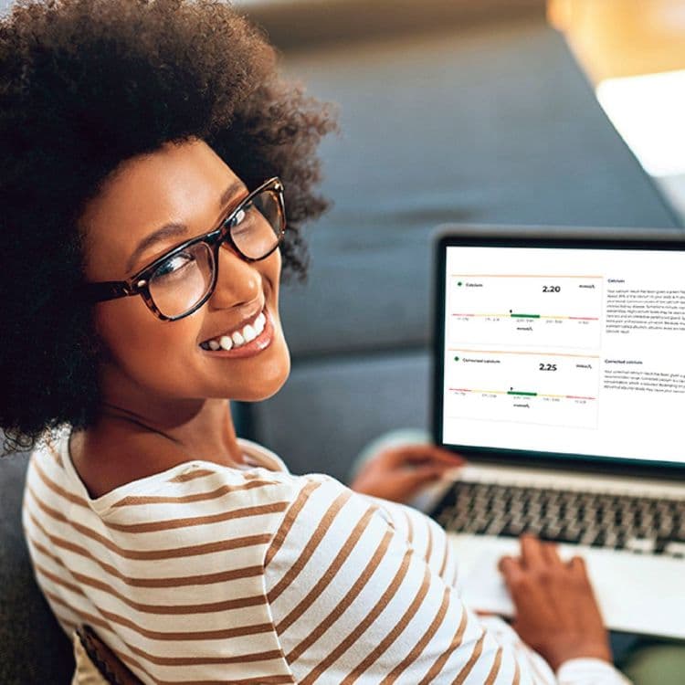 Young woman looking back at camera with her Bluecrest Wellness personal results report displayed on her laptop